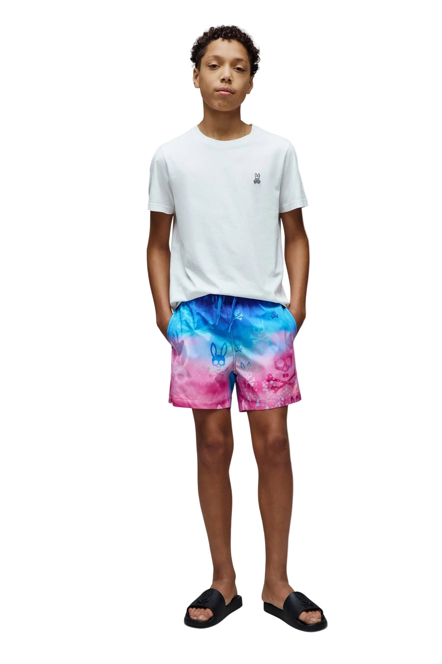 Person wearing a white t-shirt and colorful tie-dye shorts on a white background