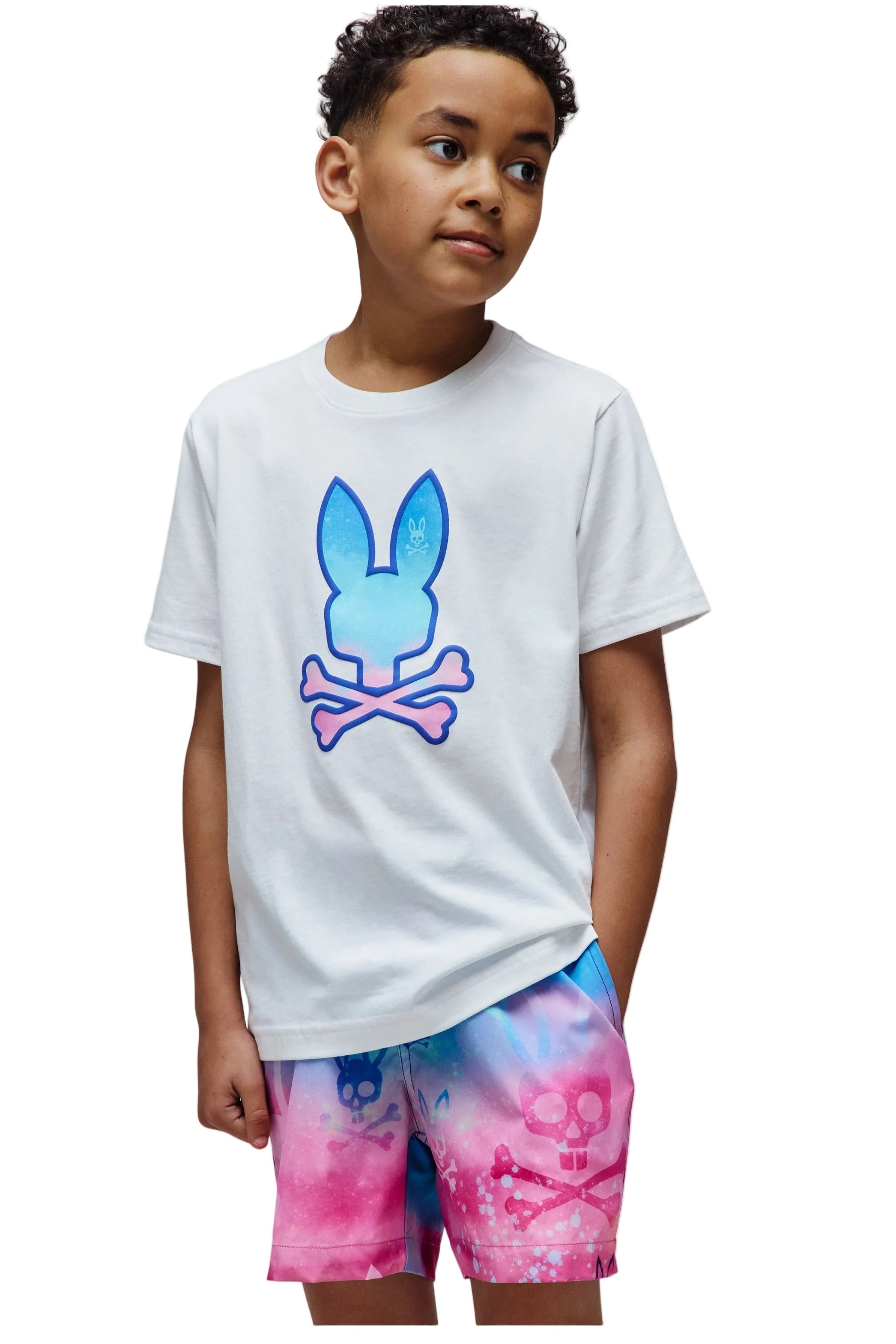Child wearing a white t-shirt with a colorful graphic and tie-dye shorts on a white background