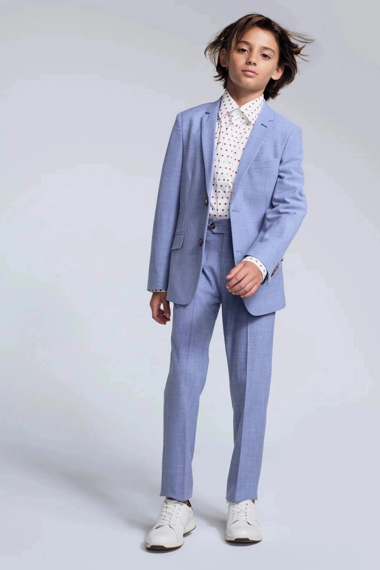 Child wearing a light blue suit with a white shirt on a plain background
