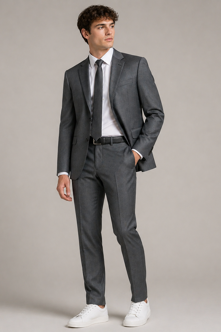 Man wearing a gray suit with white shoes on a plain background