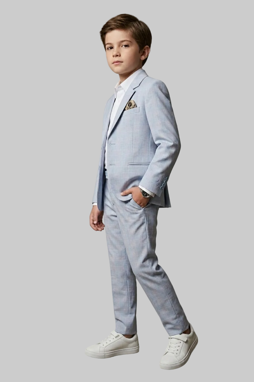Young boy in a light blue suit standing against a plain background