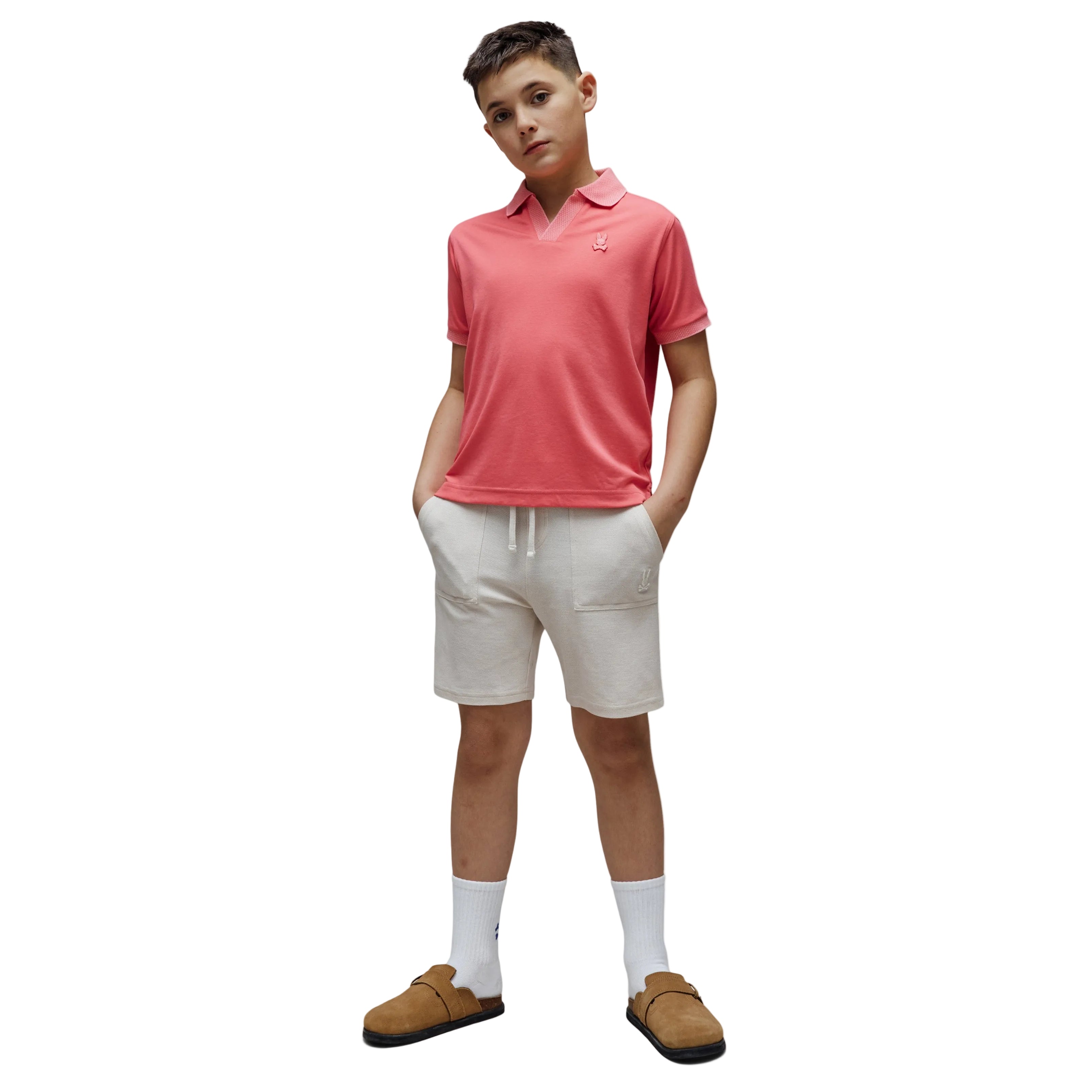 Person wearing a pink polo shirt, white shorts, and brown shoes on a white background