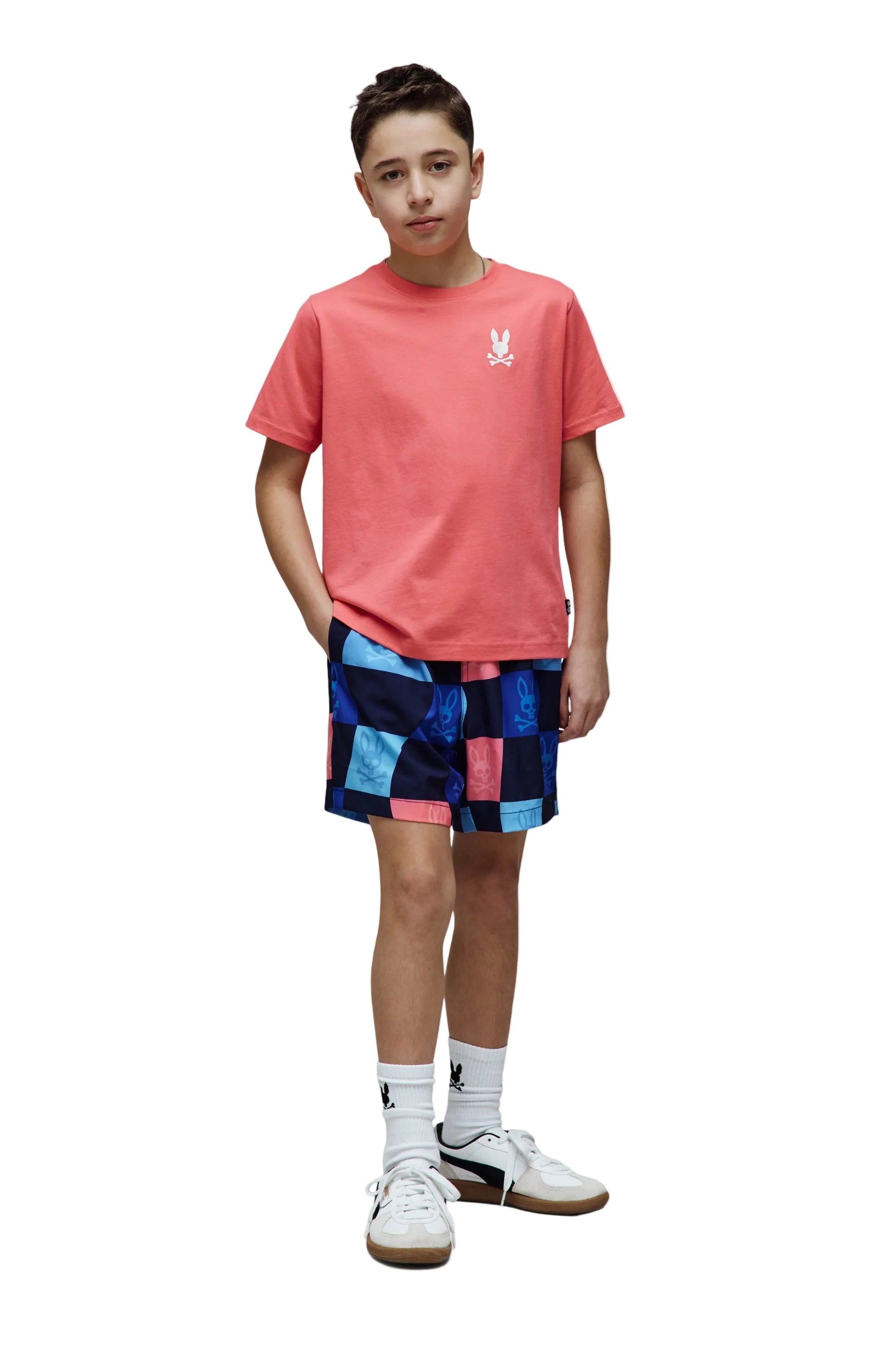 Person wearing a red t-shirt and colorful checkered shorts on a white background