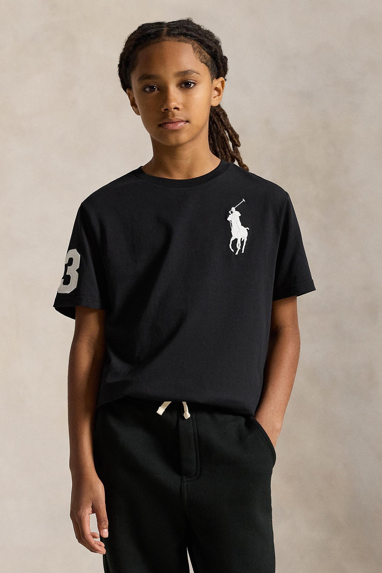 Child wearing a black t-shirt with a logo on a beige background
