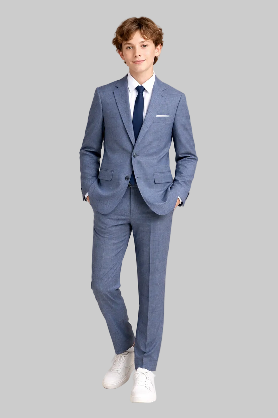 Young boy wearing a blue suit with a white shirt and white shoes on a beige background