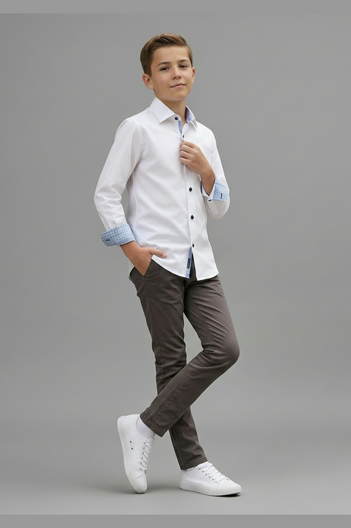 Young boy wearing a white shirt with rolled-up sleeves and brown pants on a gray background
